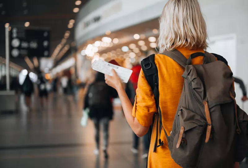 Woman at airport holding passport with boarding pass