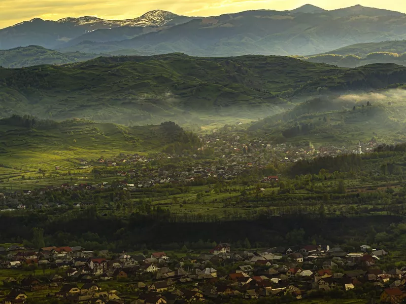 Maramures County in Romania with houses from Leud and the mighty Carpathian Mountains behind