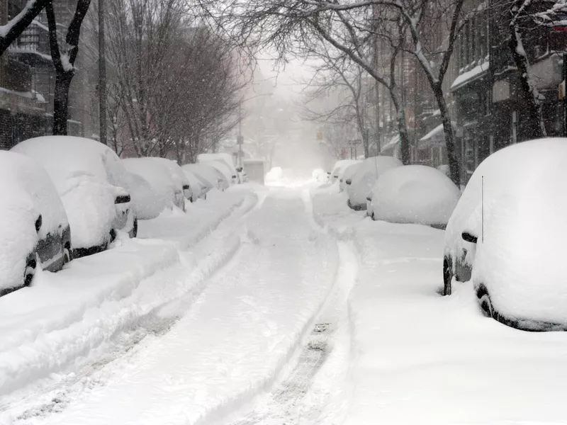 Looking down a road full of snow covered cars