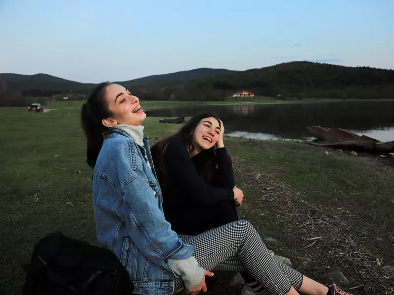 Happy girls by the lake at sunset