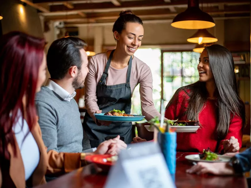 Waitress serving food to a group of customers at a restaurant