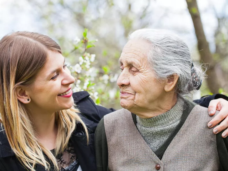 Happy elderly woman with carer outdoor - springtime