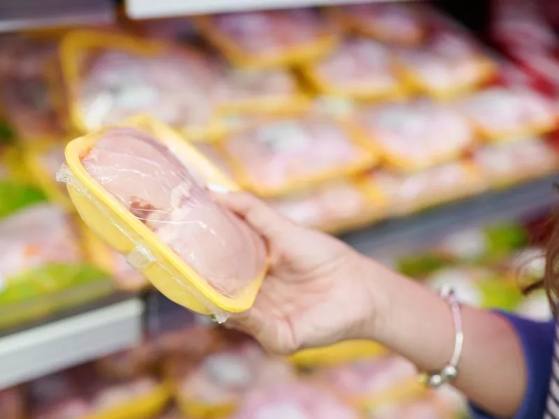 Woman choosing packed fresh chicken