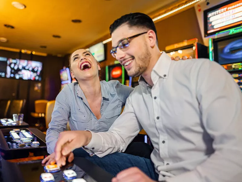 Two friends gambling on slot machine at the casino