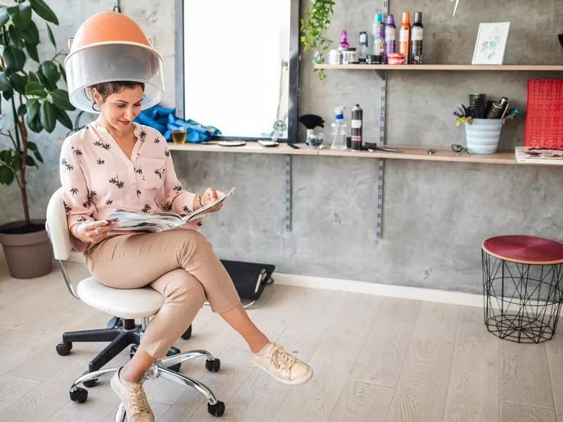 Woman sitting under hair dryer in salon