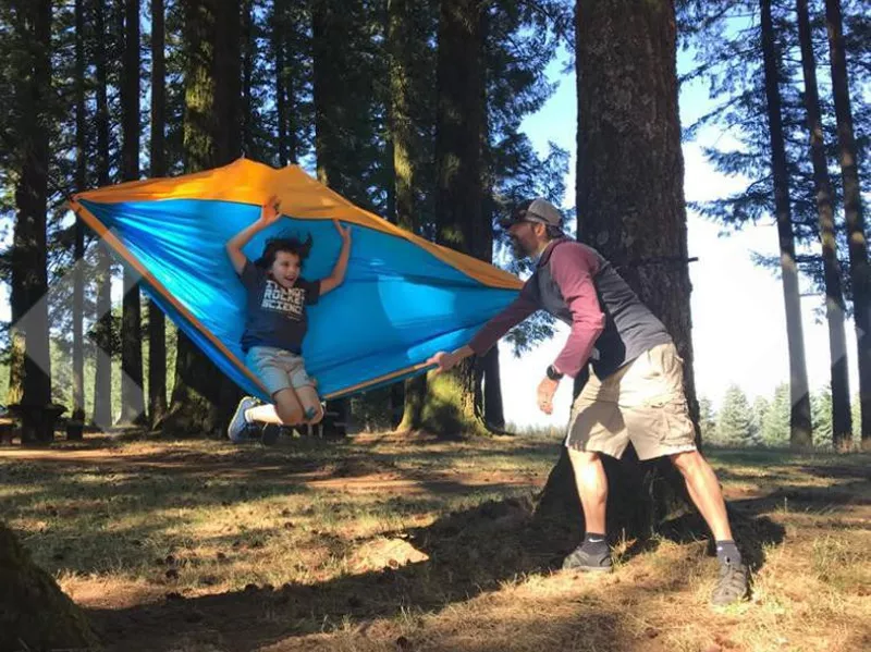 Dad swinging boy in parachute hammock