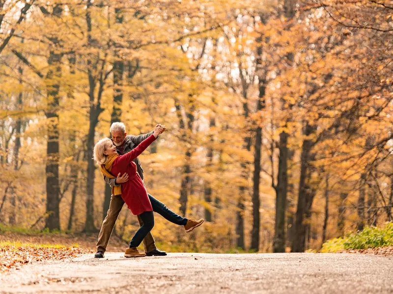 Senior couple dancing on a forest road