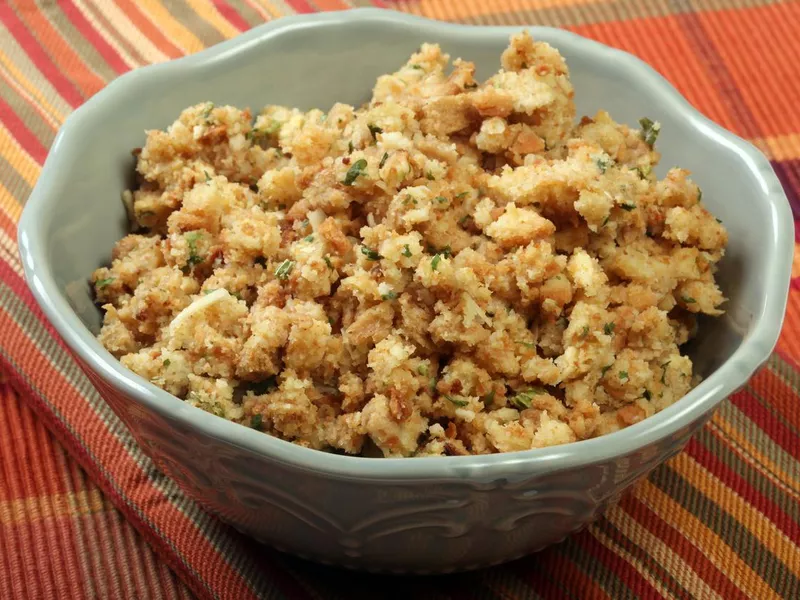 White decorative bowl of stuffing on a striped tablecloth