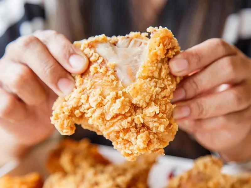 Hand holding Fried chicken and eating in the restaurant