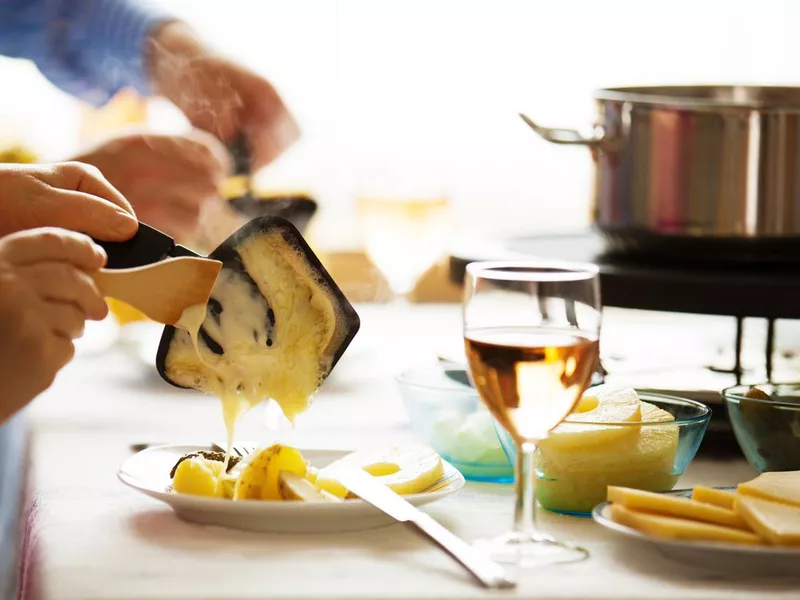 Family eating raclette with white wine