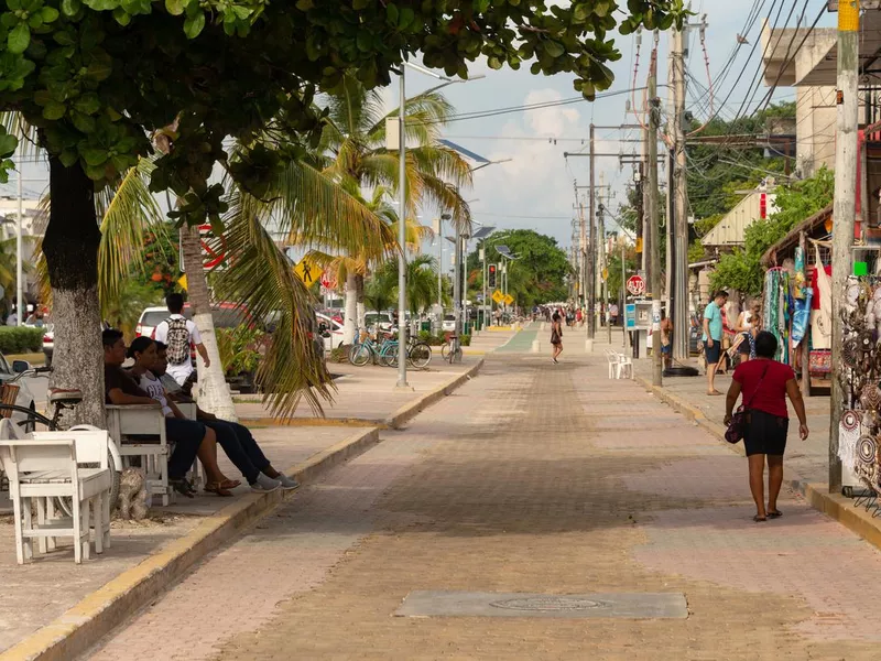 People walking on the sidewalk on Avenida Tulum.