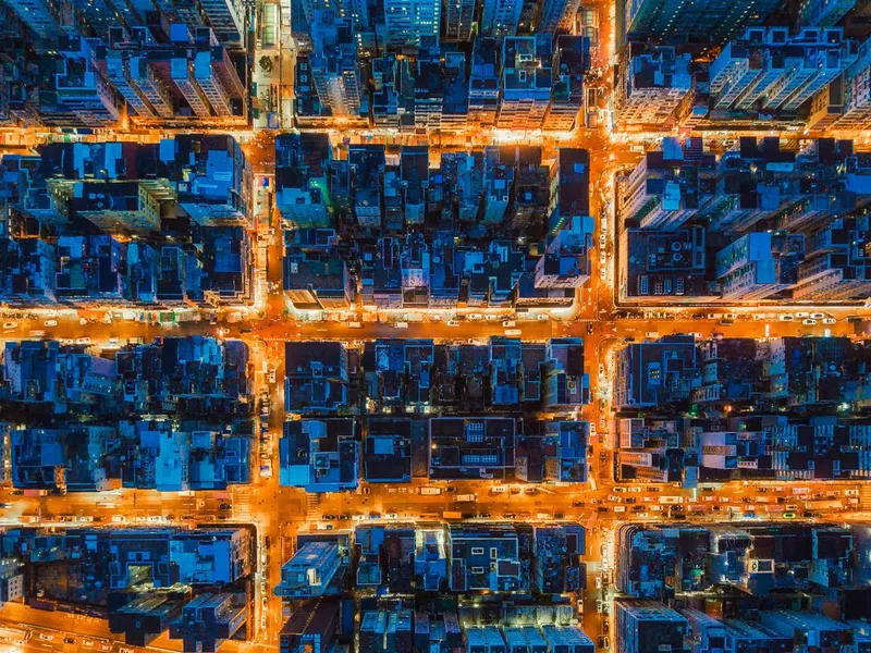 Aerial view of intersection in Hong Kong Downtown. Financial district and business centers in smart city, technology concept. Top view of buildings at night.