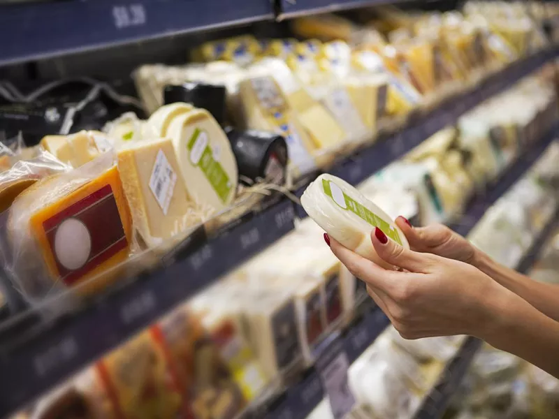 Woman buying cheese in a supermarket