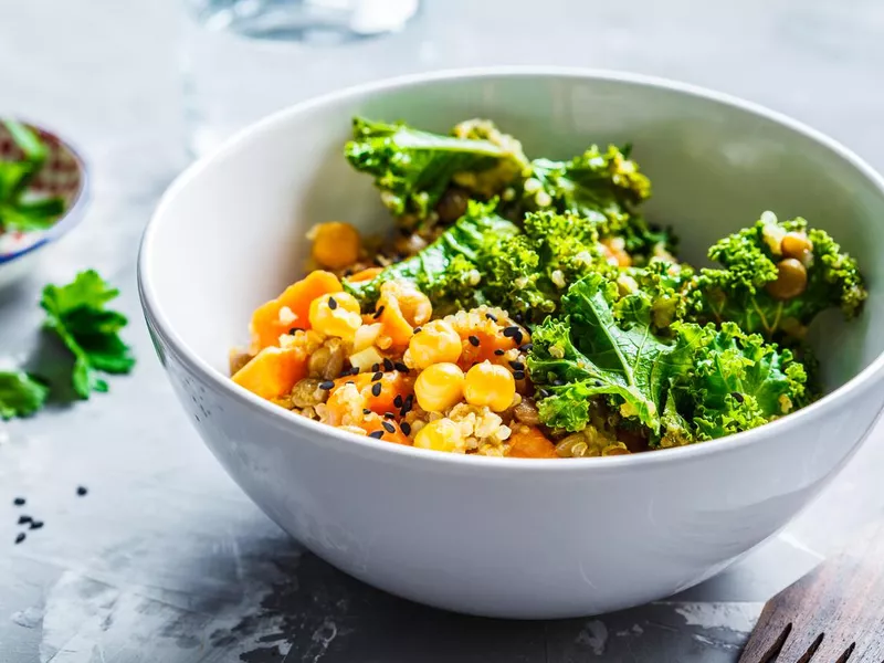 Vegan stew with chickpeas, sweet potato and kale in white bowl.