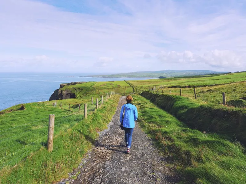 Woman trekking on Cliffs of Moher walking trail in Ireland