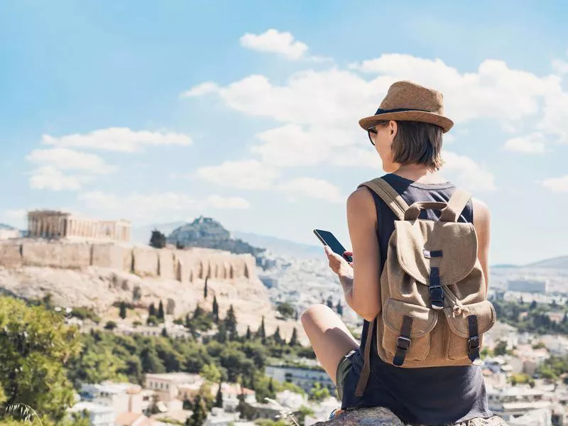 Woman using smart phone on vacations in Athens