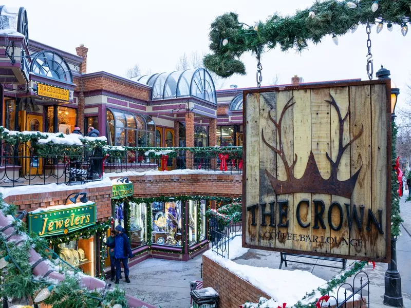 Beautiful Colorado mountain town on a snowy winter day. People walking on the street next to beautiful colorful stores in town shopping center.