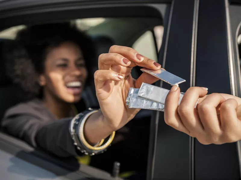 Women passing chewing gum out of the window car