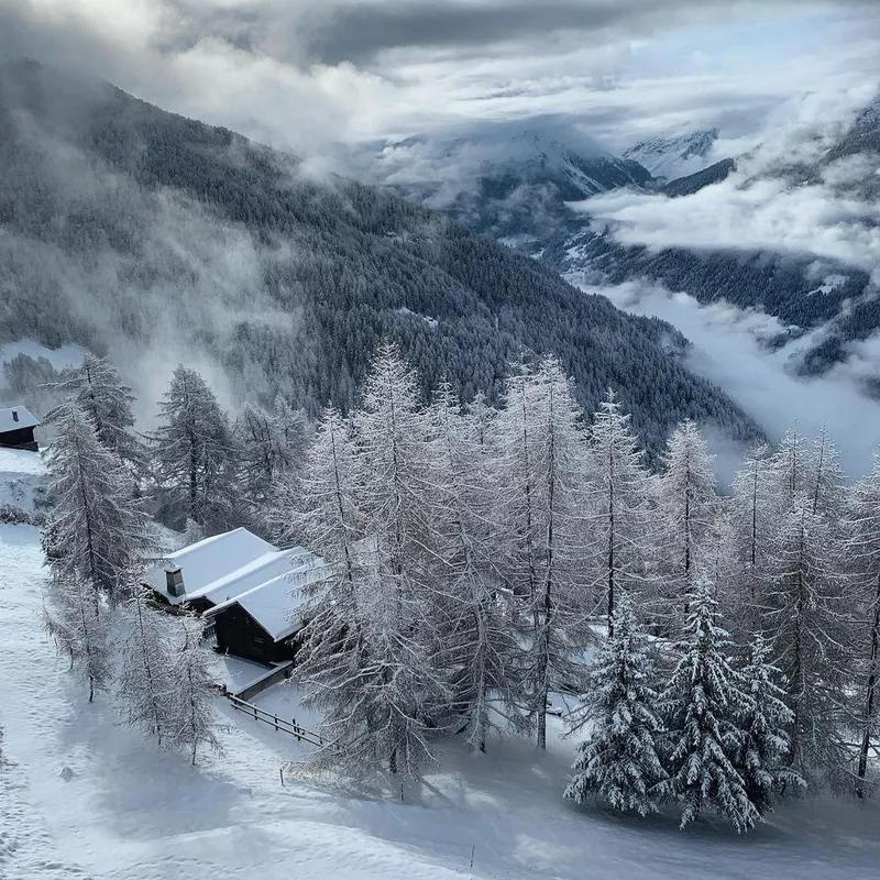 Snow covered homes, trees and mountains in Swiss Alps