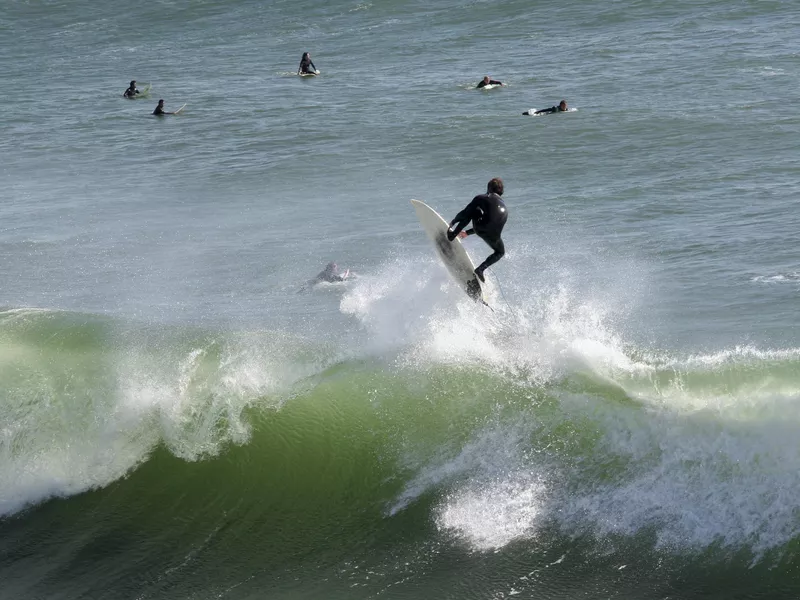 Surfer riding a wave near Lighthouse Field State Beach in Santa Cruz, Ca