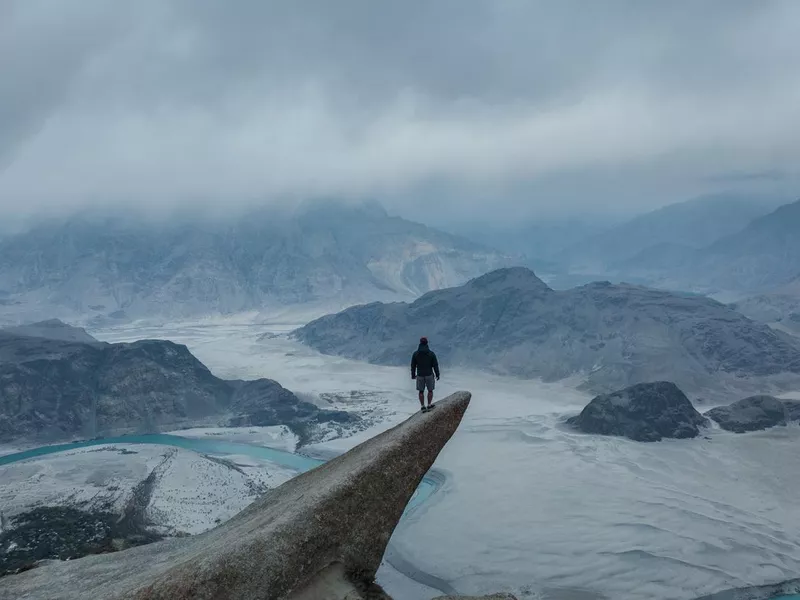 Aerial view of man standing on rock and looking at river in Himalayas