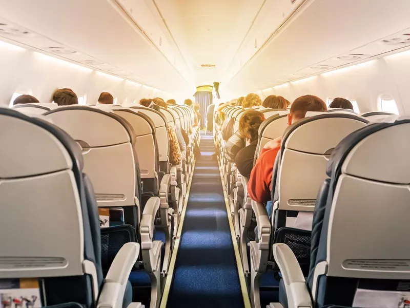 Commercial aircraft cabin with rows of seats down the aisle