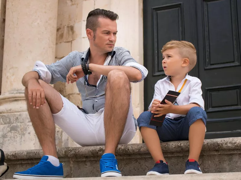 Father and son sitting on steps while relaxing in the city.