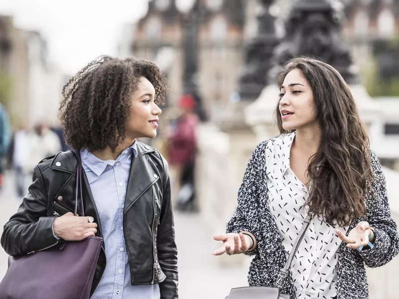 Two female friends talking outdoors in Paris, France