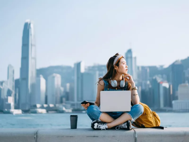 Asian woman sitting cross-legged by the promenade