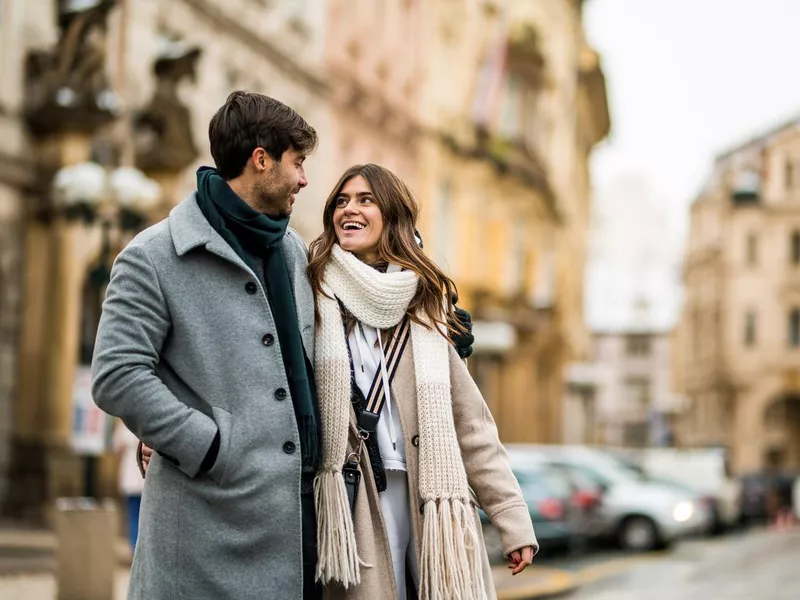 Happy couple embracing and walking on city street on a winter day in Prague.