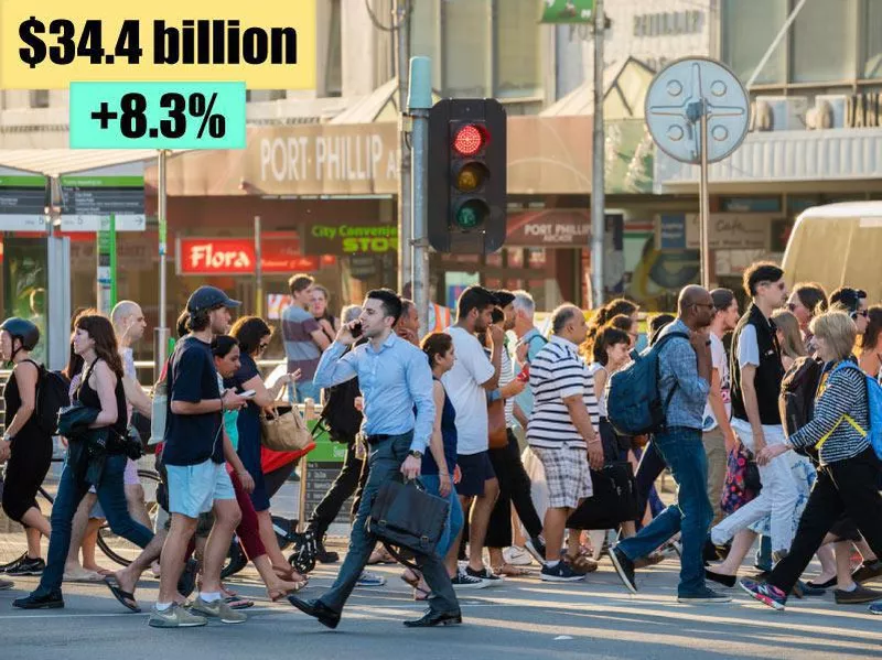 People walking across a busy crosswalk in Melbourne at sunset