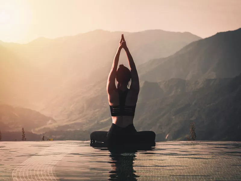 Beautiful Attractive Asian woman practice yoga Lotus pose on the pool above the Mountain peak in the morning in front of beautiful nature views,Feel so comfortable and relax in holiday,Warm tone