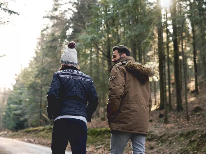 Rear view of father and son walking in autumn forest