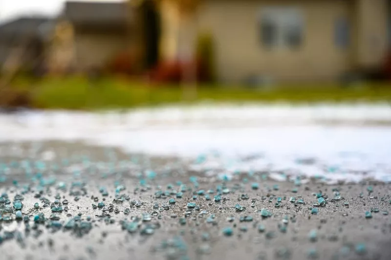 Ground level closeup view of rock salt ice-melt on concrete with snow