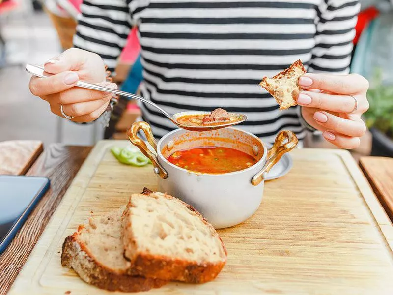 Person eating soup and bread in Hungary