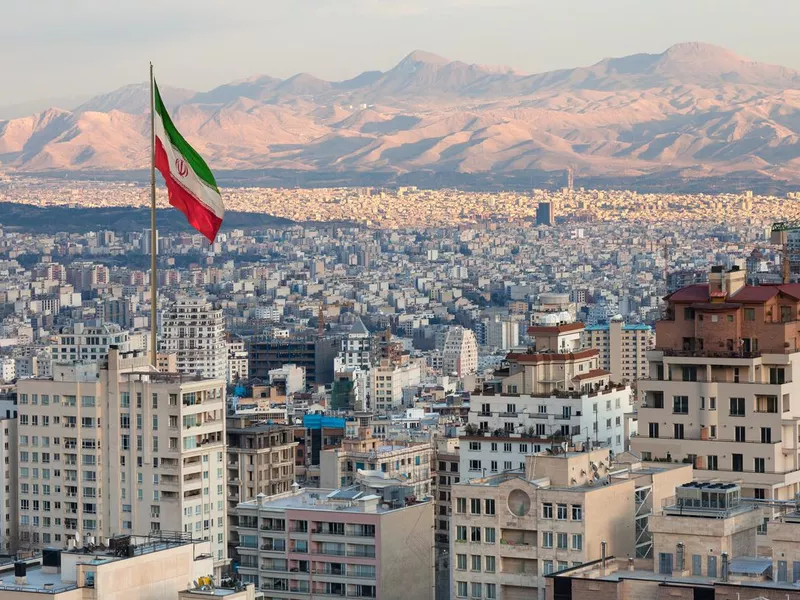 Aerial view of Tehran Skyline at Sunset with Large Iran Flag Waving in the Wind