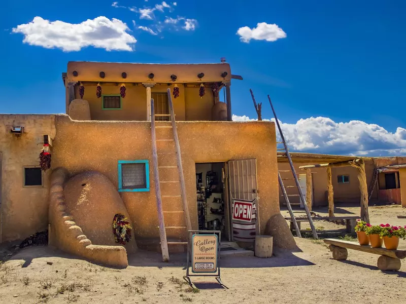 Taos Pueblo where indigenous people have lived for over 1000 years - door standing open and flowers set out under beautiful sky