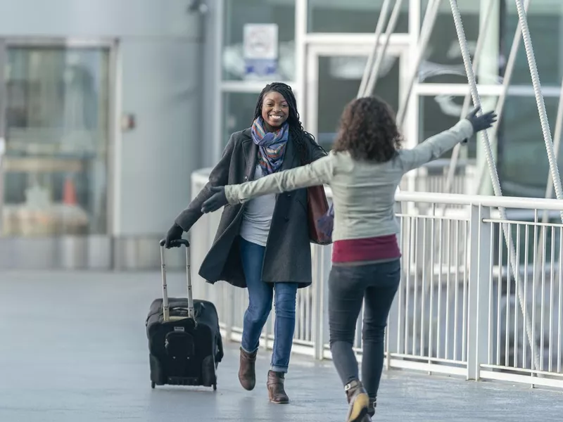 Two Friends Greeting Each Other At Airport